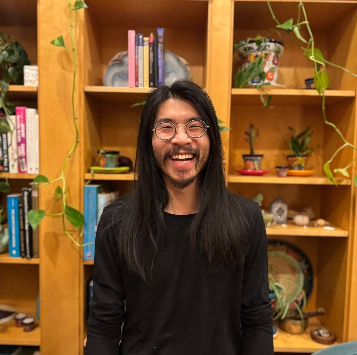 Alex Lai smiling in front of his books.